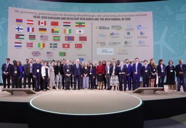 Lots of people standing on a podium with their countries flags in the background following the launch of the UAE and Canada's Breakthrough Initiative at COp28