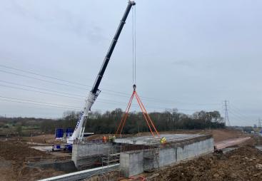 A crane lifting concrete beams to construct a road bridge