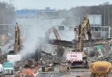 A motorway bridge being demolished using several large excavators