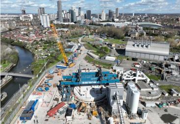 An aerial shot of a construction site with a yellow crawler crane and a large blue gantry crane