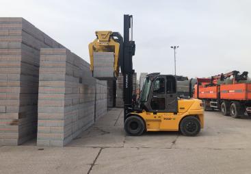 A yellow forlift stacking concrete plinths