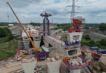 An aerial picture of a viaduct under construction with a yellow crane and red formwork.