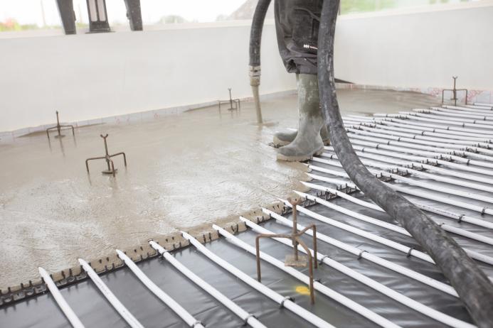 Concrete being poured inside a building over an underfloor heating system