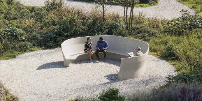 Two people sitting on a curved concrete bench in a park