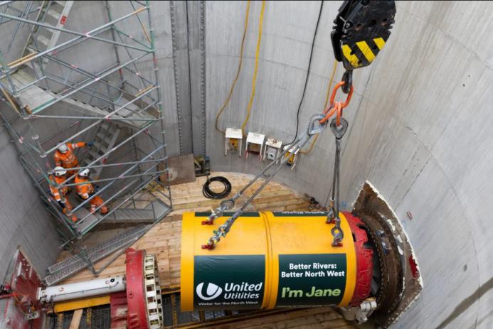 A yellow TBM being lowered into a launch pit