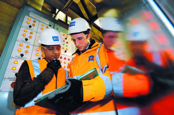 Two people in PPE looking at a laptop