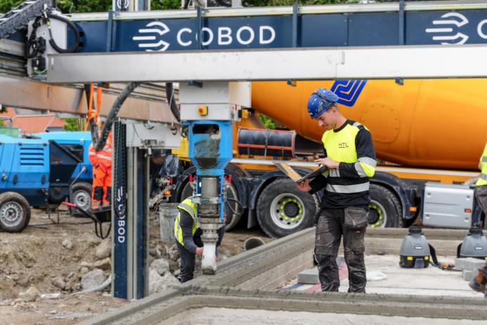 A man in PPE using a laptop on a construction site