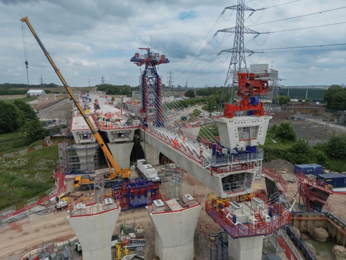 An aerial picture of a viaduct under construction with a yellow crane and red formwork.