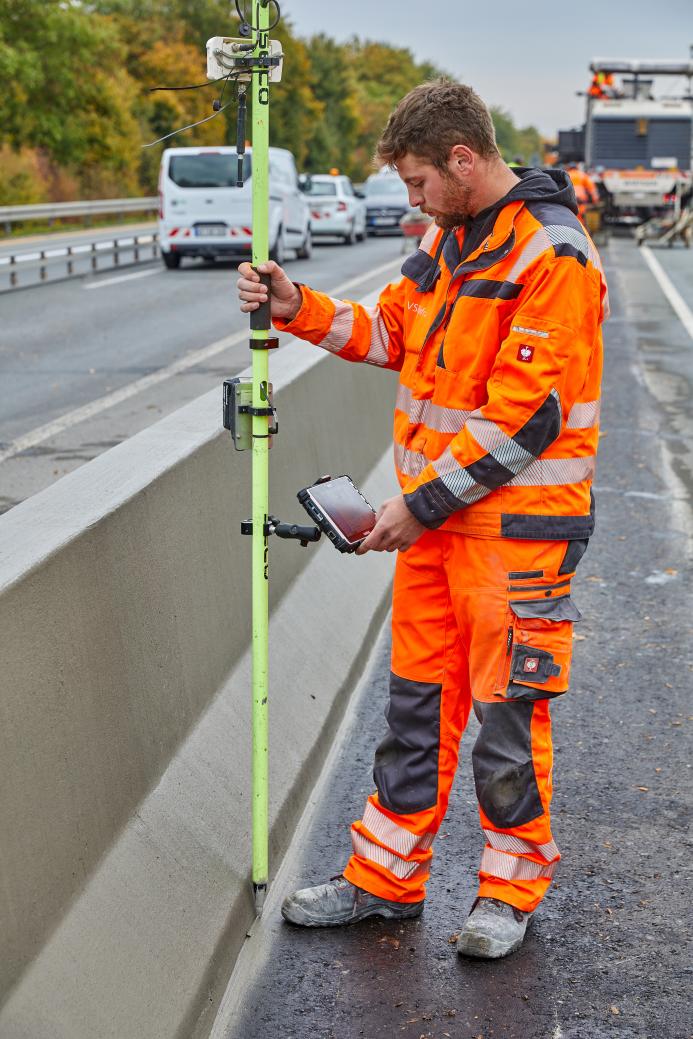 A construction worker in orange PPE working on a road