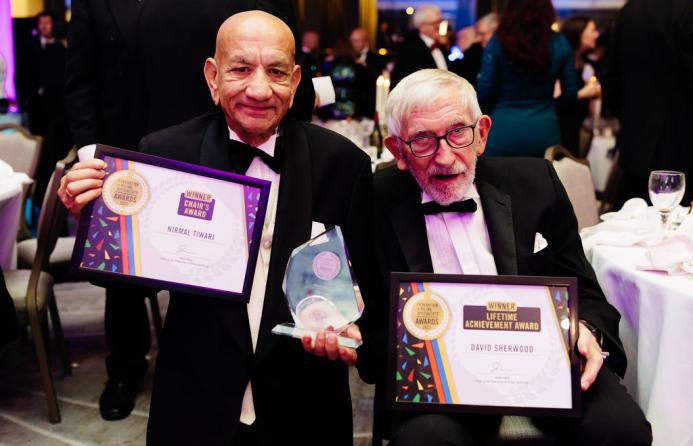 Two old men in DJs holding award certificates