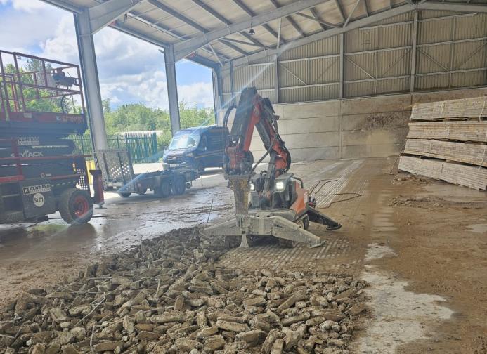 A demolition robot using a hammer to break a concrete floor