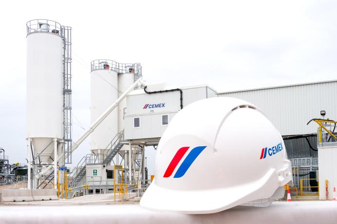 A white hard hat with a cement plant in the background