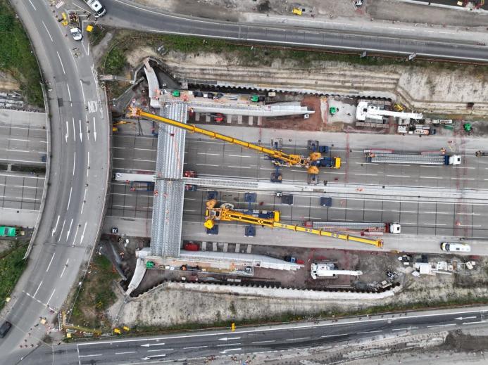 An aerial picture of two yellow cranes building a bridge