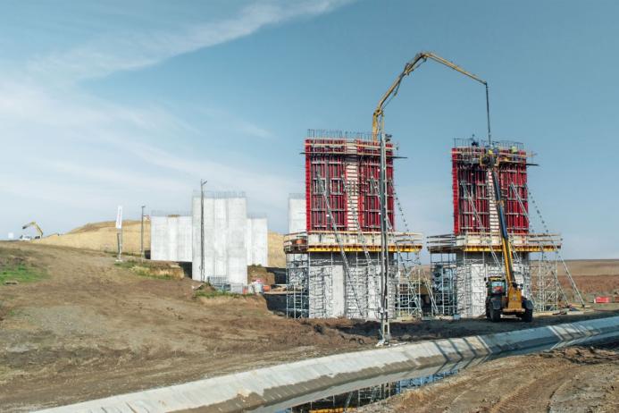 Two bridge piers under construction covered in scaffolding