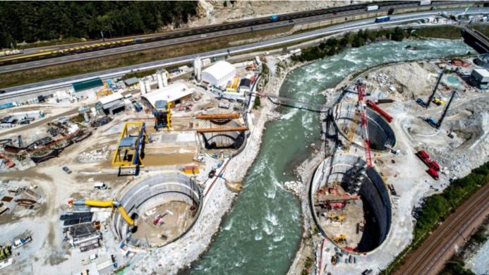 A large construction site divided by a bend in a river