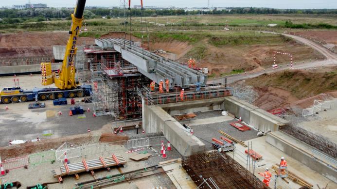 A construction site with a yellow crane and a bridge under constrcution