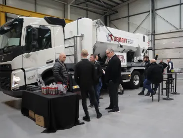 A group of men socialize in front of a volumetric concrete mixer at Volumetric's first Christmas open day was held at its new facility in Wednesbury, in the West Midlands. 