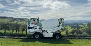 A white mobile concrete mixer in a green field