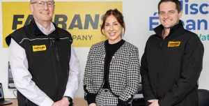 Three people, two men and a woman, standing with their hands clasped, looking at the camera