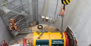 A yellow TBM being lowered into a launch pit