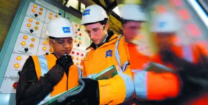 Two people in PPE looking at a laptop