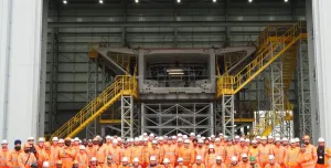 A group of people orange PPE standing in front of a precast concrete bridge pier