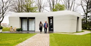 Two people walking down the garden path from a single story house