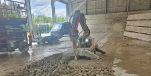 A demolition robot using a hammer to break a concrete floor