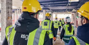 A group of people in PPE walking away from the viewer inside an under construction office building