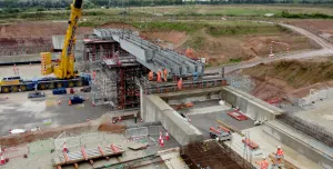 A construction site with a yellow crane and a bridge under constrcution