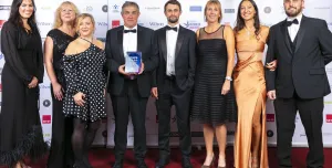 A group of people in evening wear in a line, on a stage accepting an award