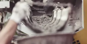 Concrete being poured from a mixer into a container. A dynamic action image shows wet concrete being dispensed from a mixer into a container, capturing the essence of construction work and the creation of solid foundations in building projects.