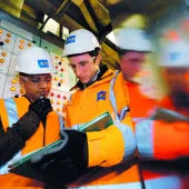 Two people in PPE looking at a laptop