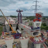 An aerial picture of a viaduct under construction with a yellow crane and red formwork.