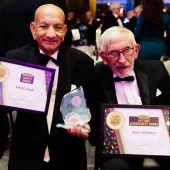 Two old men in DJs holding award certificates