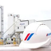 A white hard hat with a cement plant in the background