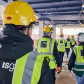 A group of people in PPE walking away from the viewer inside an under construction office building