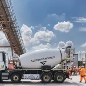 A white cement mixer and men in orange PPE