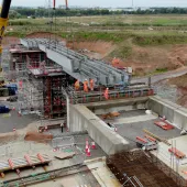 A construction site with a yellow crane and a bridge under constrcution