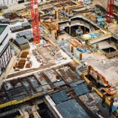 A construction site from above with a red tower crane and yellow excavators