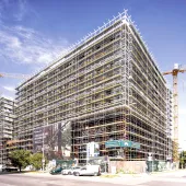 An under construction mid-rise building covered in scaffolding