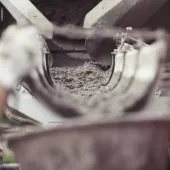 Concrete being poured from a mixer into a container. A dynamic action image shows wet concrete being dispensed from a mixer into a container, capturing the essence of construction work and the creation of solid foundations in building projects.