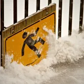 A health and safety sign of a person slipping on ice, covered in snow