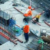 Two PPE clad construction workers install rebar ties