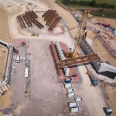 A yellow crane lifts beams into place for the Gloucestershire Way bridge, which will span the new A417 Missing Link and eight lanes of traffic