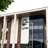 An external view of Teeside University’s Net Zero Industry Innovation Centre (NZIIC), a multi-storey building with a glass, red brick and white render facade.