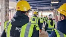 A group of people in PPE walking away from the viewer inside an under construction office building