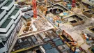 A construction site from above with a red tower crane and yellow excavators