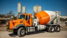 A bright orange concrete mixer truck at a cement plant