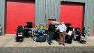 Two men shake hands infront of a range of floor grinding equipment, which is placed outside a grey warehouse with two, big red doors